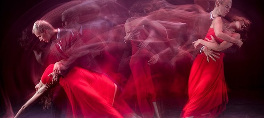 Женщина в красном платье и мужчина в танце. Расплывчатое движение